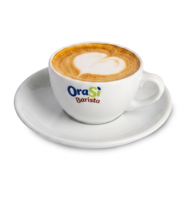 Bílý šálek na cappuccino se srdcovou latte art kresbou, nápis "OraSì Barista", na podšálku, bílé pozadí