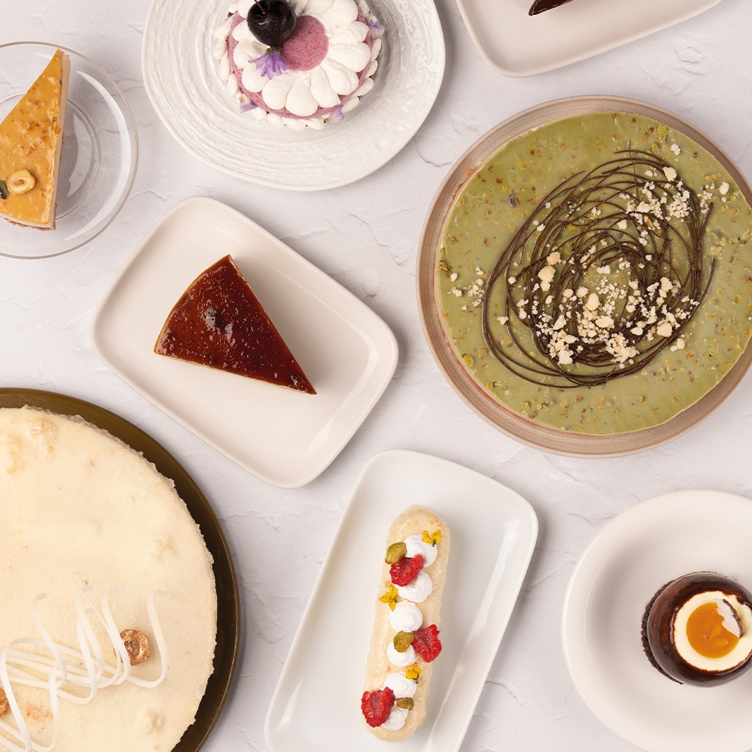Pohled shora na dezerty: cheesecake, flan, pistáciový koláč, eclair a pohárky s čokoládovou pěnou
