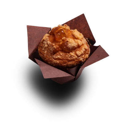 Zlatavý muffin s drobenkovým streuselem a ovocnou náplní, v hnědém papírovém košíčku, na bílém pozadí.