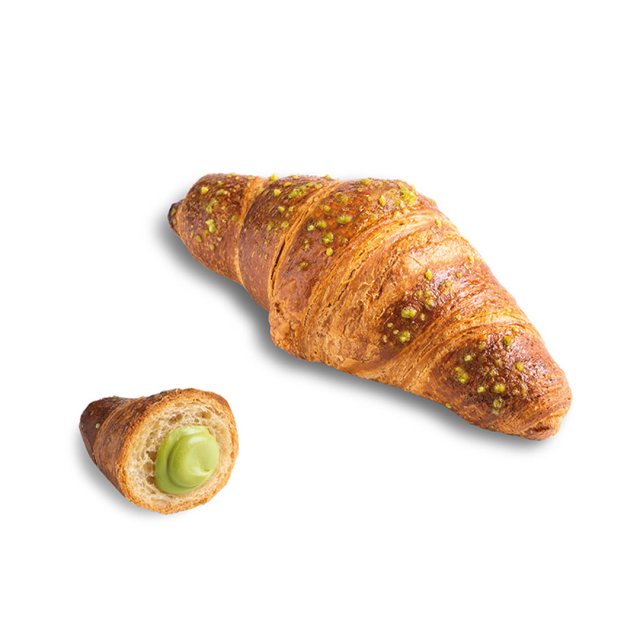 Zlatý croissant posypaný drceným pistáciemi, menší kousek rozříznutý odhaluje pistáciový krém.