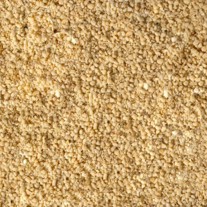 Detailní záběr na jemný, zrnitý, světle žlutý prášek s hrubou, drobivou strukturou pokrývající celý záběr.