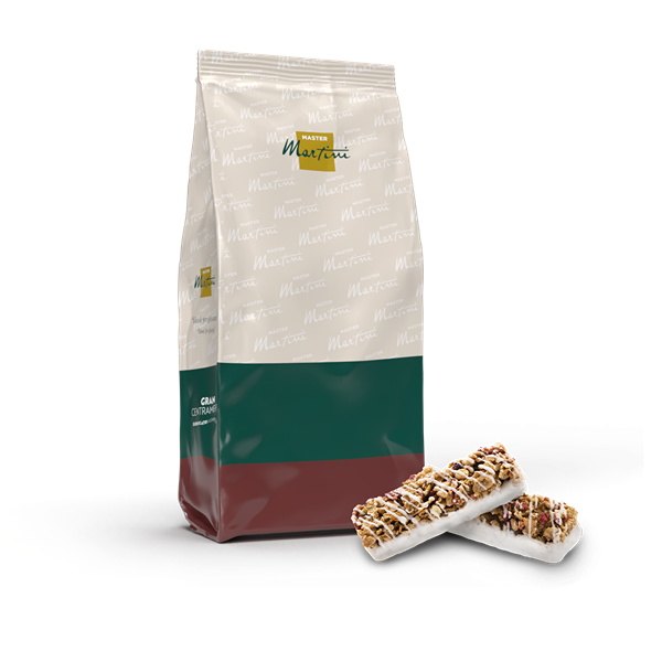 Sáček Master Martini se zeleno-červenou etiketou vedle dvou granola tyčinek s bílou čokoládou