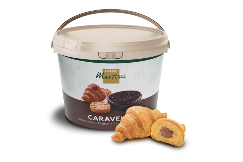 Béžový kbelík čokoládového krému Caravel Master Martini vedle dvou croissantů, jeden plněný čokoládou.